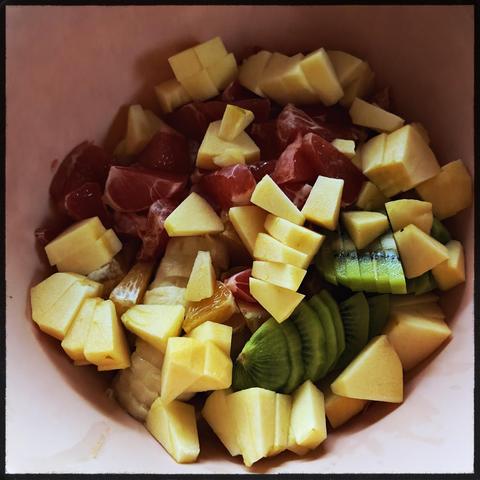 Eine bunte Mischung aus Obst  in einer rosa Schälchen: Kiwi, Orange , Grapefruit, Apfel.