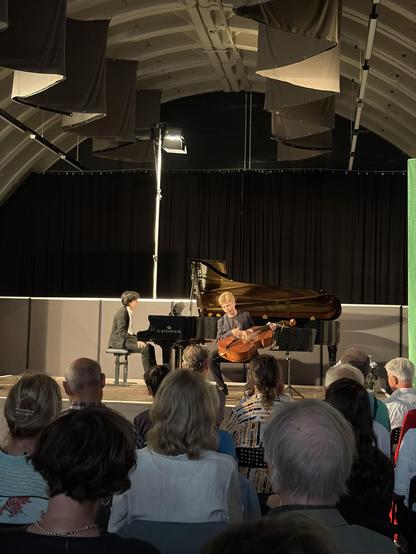 Zwei Musiker, ein Pianist und ein Cellist , treten auf einer Bühne vor einem Publikum auf.