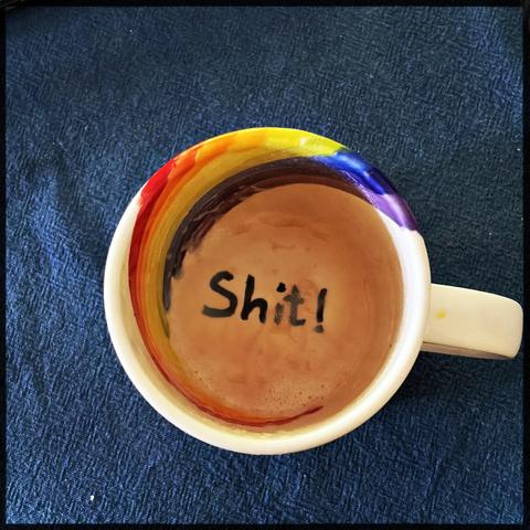 Tasse Kaffee. Aber leer. Auf dem Grund steht das Wort "Shit!" 
Die Tasse hat innen auf einer Seite ein Regenbogen der sich über den Rand nach außen zieht.