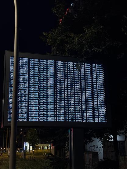 A glowing digital display shows an error log from a system journal, listing multiple instances of "Failed to write entry" with details about byte sizes and item counts. The scene is set at night, with a visible city backdrop and foliage.