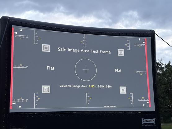 An image of a test screen displaying a "Safe Image Area Test Frame" with measurement grids, a central target, and labels indicating "Flat" along the sides. The viewable image area is noted as 1.85 (1998x108